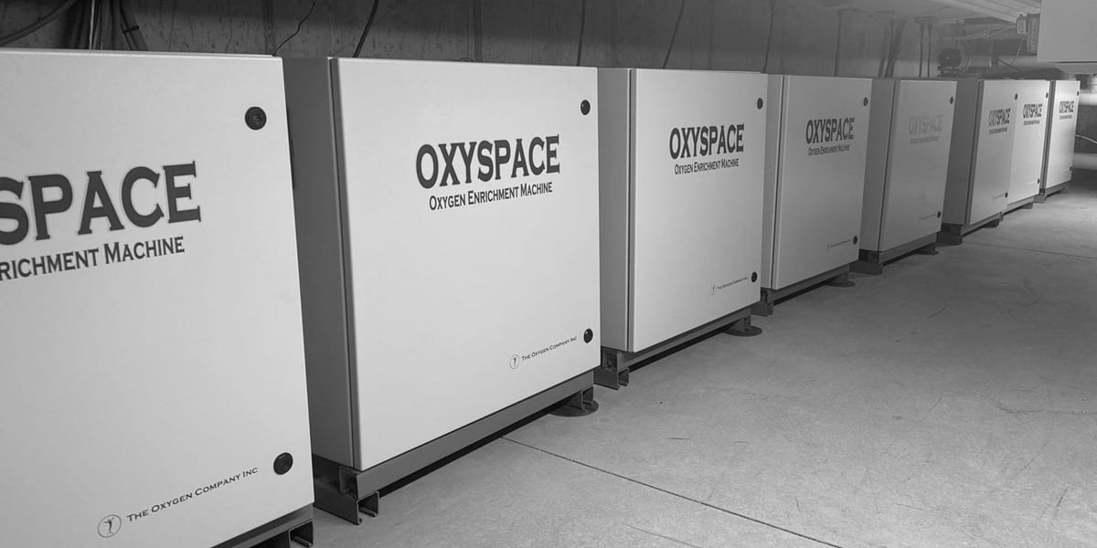 A long row of OxySpace oxygen enrichment machines, made by The Oxygen Company, Inc., installed along a mechanical room wall.