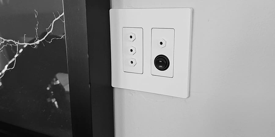 A three-port oxygen outlet plate beside a round room-control plate on a light wall.