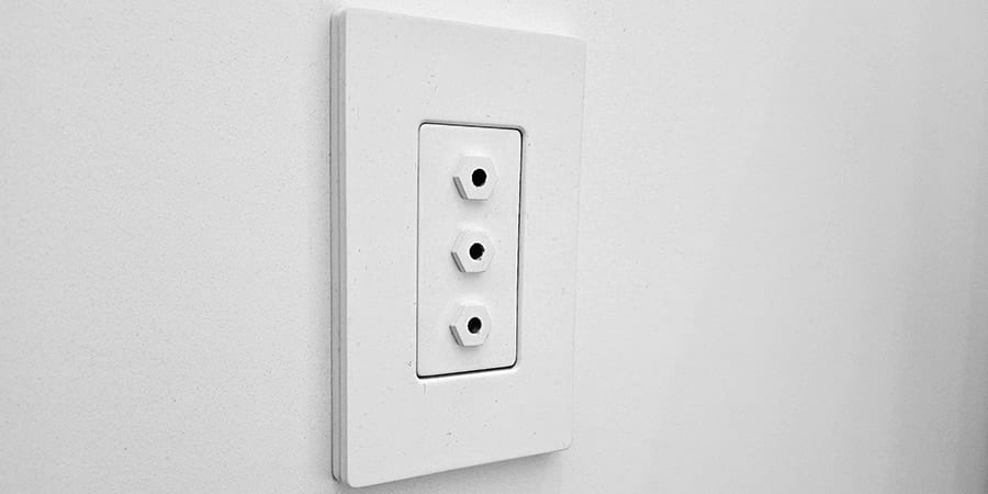 A white three-port oxygen outlet plate set into a pale wall.